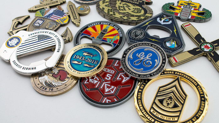 Pile of custom challenge coins in military, corporate and veteran designs